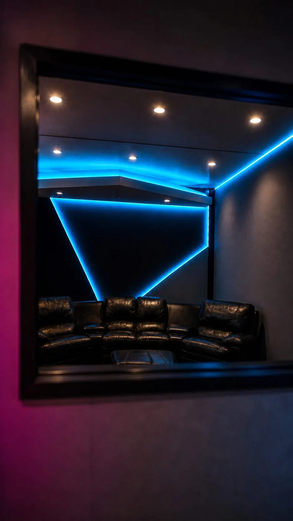 A window from the control room through to the lounge, leather recliners under blue cove lighting